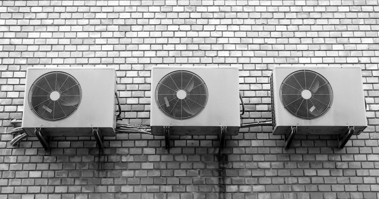 ad-technics---drie-buitenairconditioningunits zijn achter elkaar op een bakstenen muur gemonteerd, waardoor het eenvoudig is om onderhoud te plannen met AD Technics.